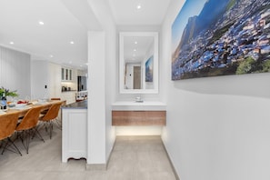 A modern kitchen with white cabinets, a built-in island, and a large cityscape painting on the wall.