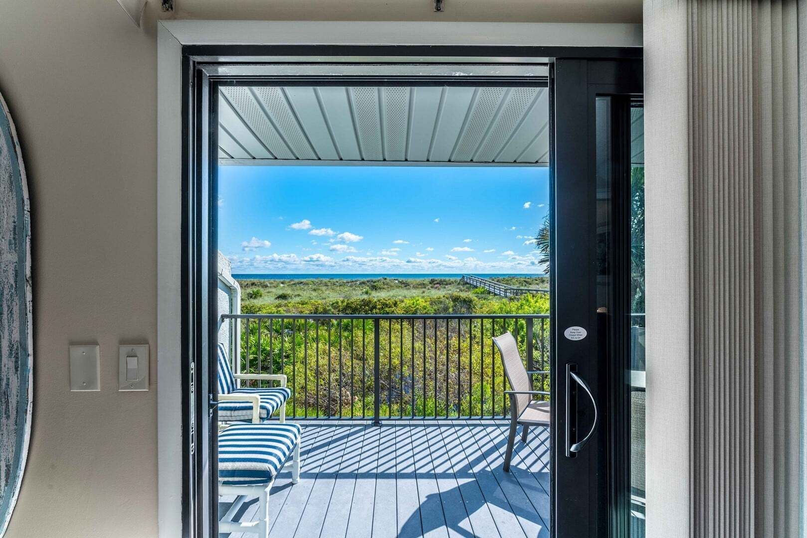 A balcony with a view of a beach and a clear sky.
