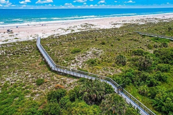 A coastal area with a paved walkway leading to the beach.