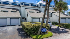 A residential building with multiple garage doors, a well-maintained hedge, and a sign indicating the location as 'Clipper North.'