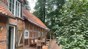 Un bâtiment traditionnel en briques, avec un toit en tuiles, des bancs en bois et un chemin en briques.