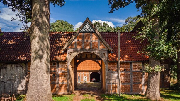 Un bâtiment traditionnel en briques, doté d’une grande entrée en arc de cercle et d’un chemin menant à un tunnel.