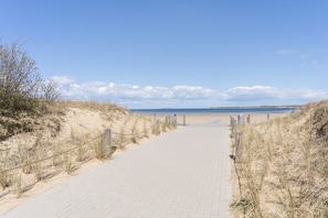A paved pathway leading to a beach with a clear sky and dunes on either side. - A renovated historic fisherman's cottage in Freest, 5 minutes from the beach (Kröslin)
