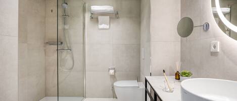 Une salle de bain moderne avec une douche à parois de verre, des toilettes et un lavabo agrémenté d’un grand miroir.