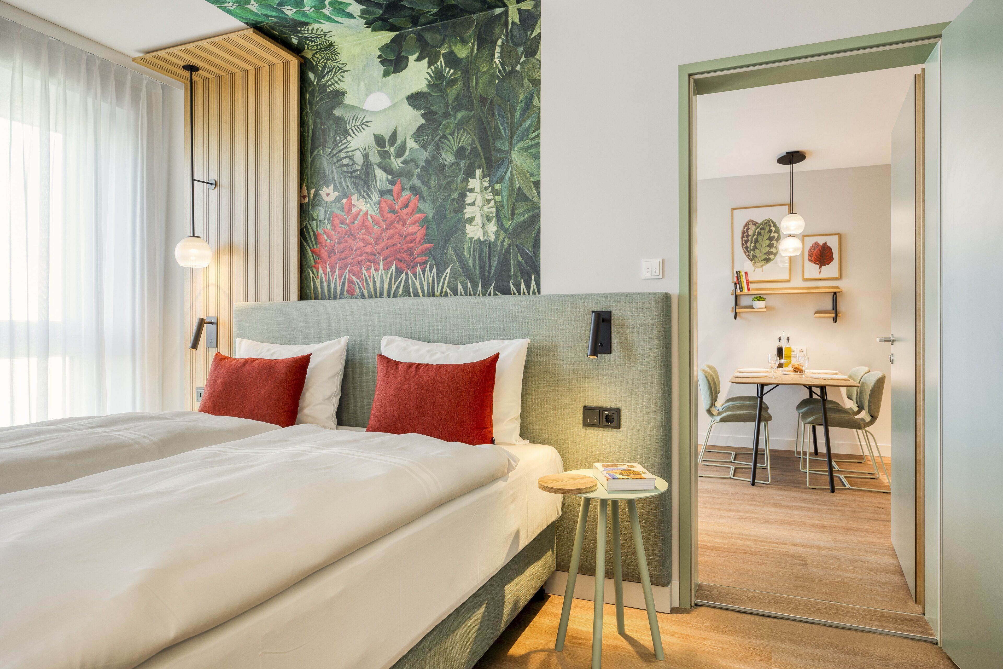 Une chambre d’hôtel avec un grand lit, un coin repas et une fresque murale.