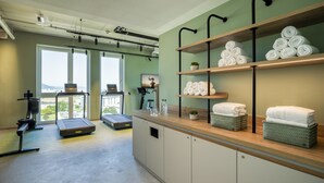 Une salle de sport équipée de tapis de course, d’un vélo d’appartement et d’une grande fenêtre donnant sur la ville.