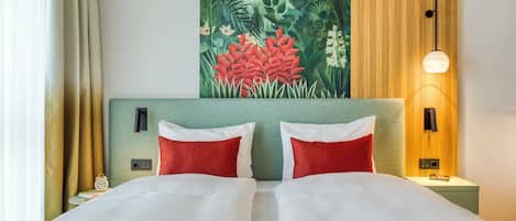 Una habitación de hotel con una cama, dos almohadas, una mesita de noche, una lámpara y un cuadro en la pared.