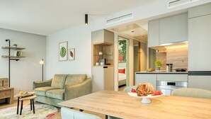 Une cuisine moderne avec une table et des chaises en bois, un four encastré et un coin repas comprenant un canapé et une petite table.