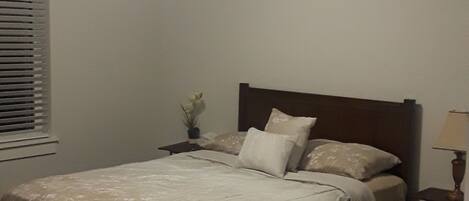 A bedroom with a bed, a ceiling fan, a nightstand, and a lamp.