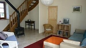 A living room with a staircase, a wooden chair, a sofa, a television, and a bookshelf. - NEW: La Grange (Ploubezre)