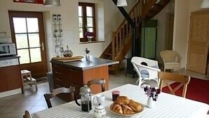 A dining area with a table set for breakfast, including croissants and a coffee pot. - NEW: La Grange (Ploubezre)