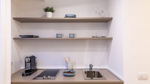 Ett kök med en kaffebryggare, en skål med frukt och en diskho.