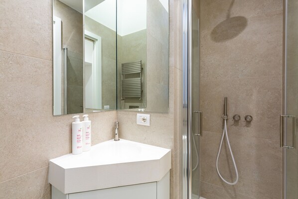Een moderne badkamer met een wit wastafel, een spiegel en een douche.