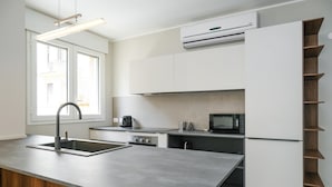 A modern kitchen with a central island, built-in appliances, and a window providing natural light. - Imbriani Suites (Rome)