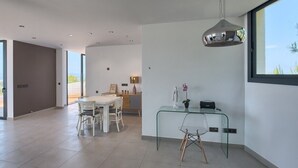 A modern interior with a dining area, a glass desk, and a large window. - Villa 'Amapola' with Mountain View, Wi-Fi and Air Conditioning (Begur)