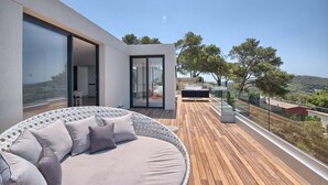 A modern balcony with a round seating area, glass doors, and a view of the landscape. - Villa 'Amapola' with Mountain View, Wi-Fi and Air Conditioning (Begur)