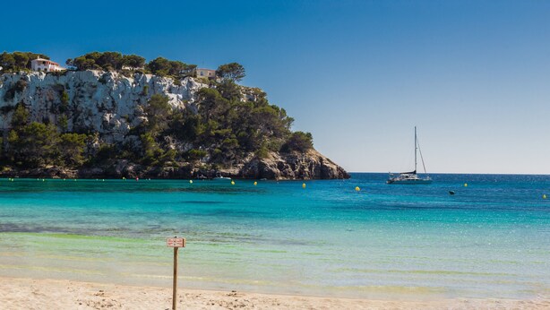 A beach with clear water, a sailboat, and a building on a cliff. - Holiday Home 'Villa Lidia' with Sea View, Private Pool and Wi-Fi (Serpentona)