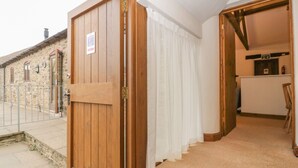 Una puerta de madera con un letrero, una cortina blanca, una escalera y un edificio de piedra al fondo.