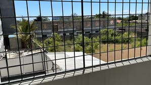A room with a barred window overlooking a residential area with houses and greenery. - Impeccable 3-bed Apartment in Mombasa (Mombasa)