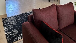A living room with a red sofa, a dining area with a table and chairs, and a kitchen visible through an open doorway. - Impeccable 3-bed Apartment in Mombasa (Mombasa)