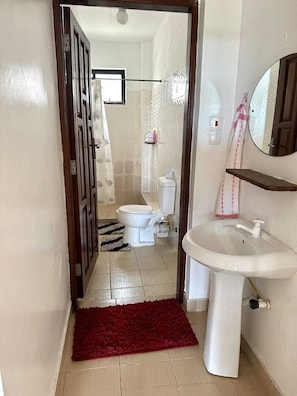 A bathroom with a white sink, toilet, and shower area.