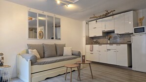 Ett kompakt bostadsutrymme med en soffa, ett litet bord och ett litet kök.
