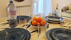 Ett matbord dukat med tallrikar, glas, en skål med apelsiner, en vattenflaska och bestick.