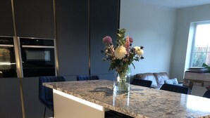 Ett modernt kök med en bänkskiva i granit, en inbyggd diskmaskin och en vas med blommor på köksön.
