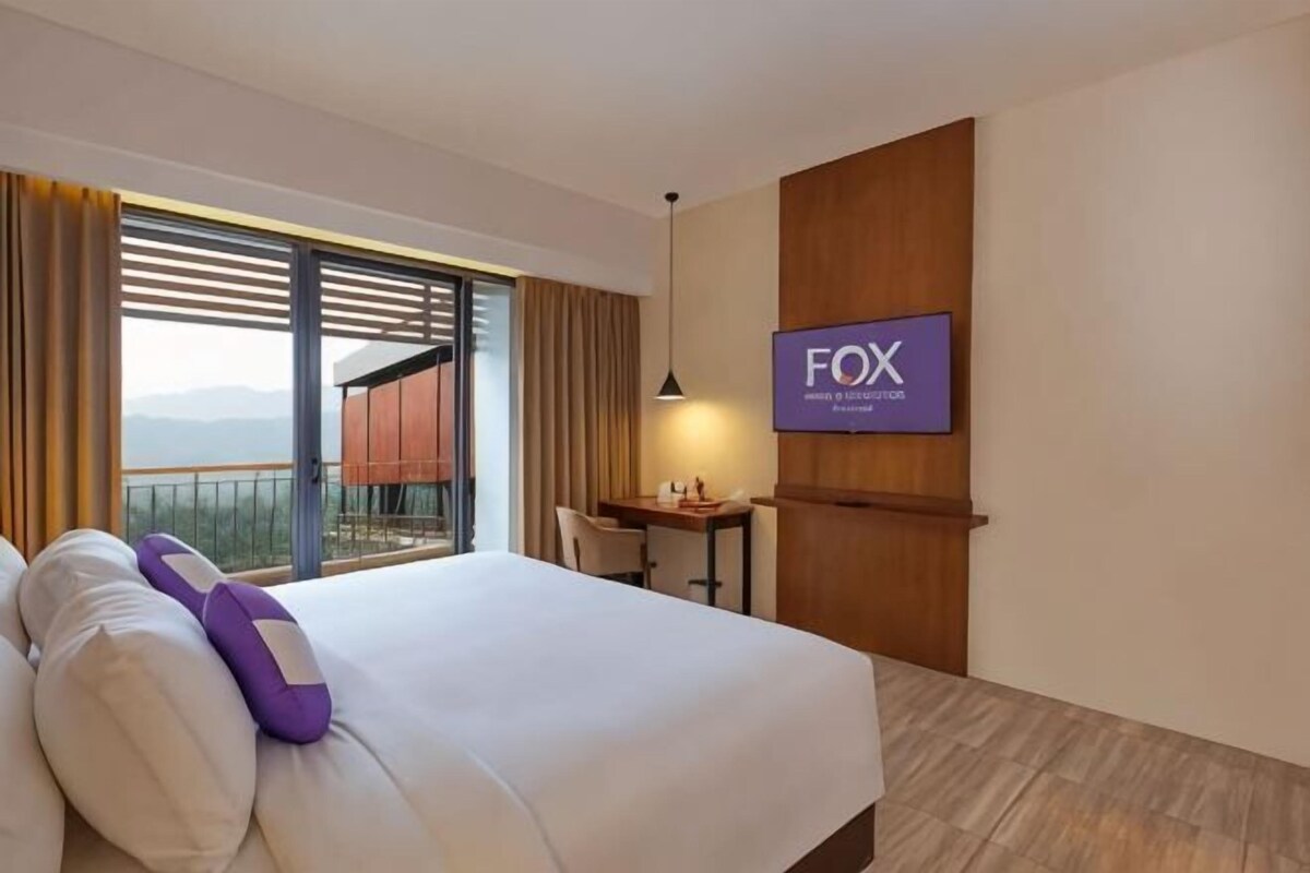 Une chambre d’hôtel avec un lit, un bureau, une chaise, une télévision et un balcon avec vue.