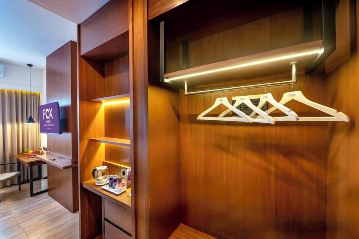 Een hotelkamer met een houten kast, een televisie en een plank met spullen.