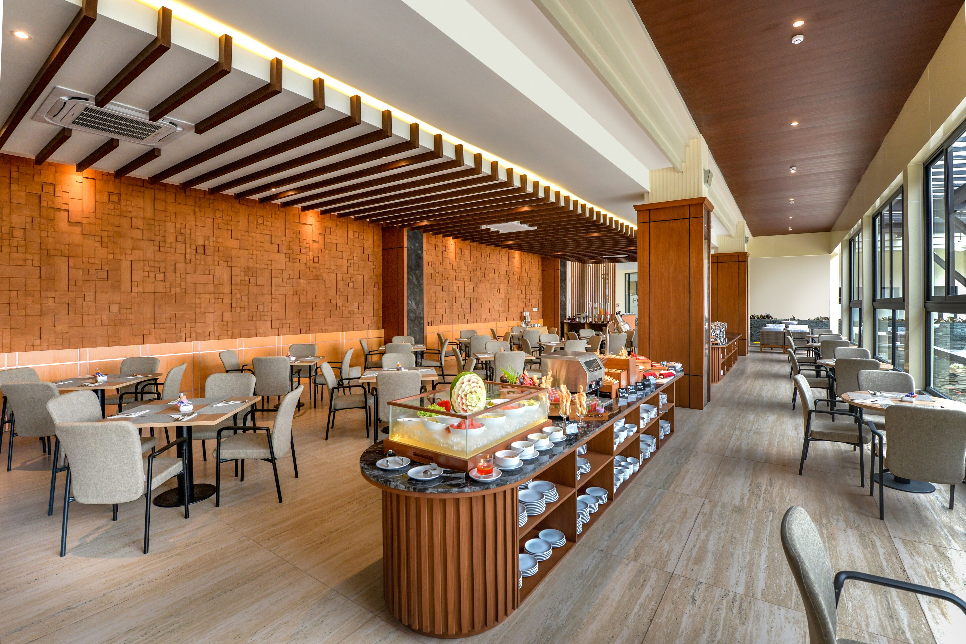 Un restaurante moderno con pared de ladrillo, techo de madera y una barra de buffet con varios platos.