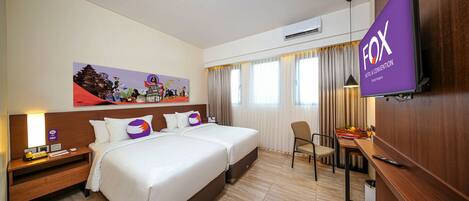 Habitación de hotel con dos camas, un escritorio, una silla, un televisor y un cuadro en la pared.