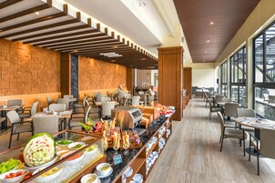 Espaço de buffet com diversas opções de comida, arranjos de assento e vista para a água.