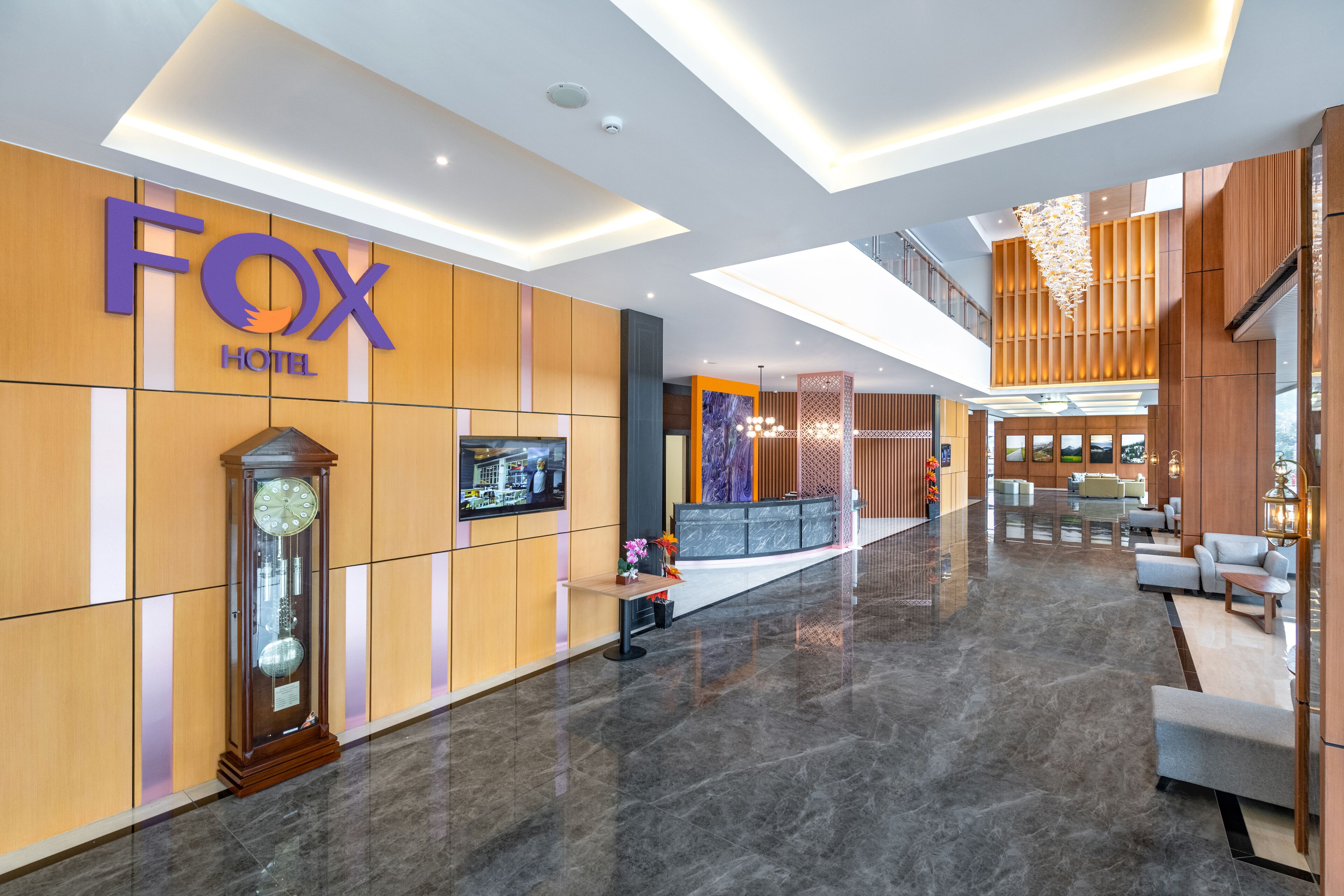 Eine moderne Hotellobby mit Empfangsschalter, Sitzgelegenheiten und einer großen Uhr.