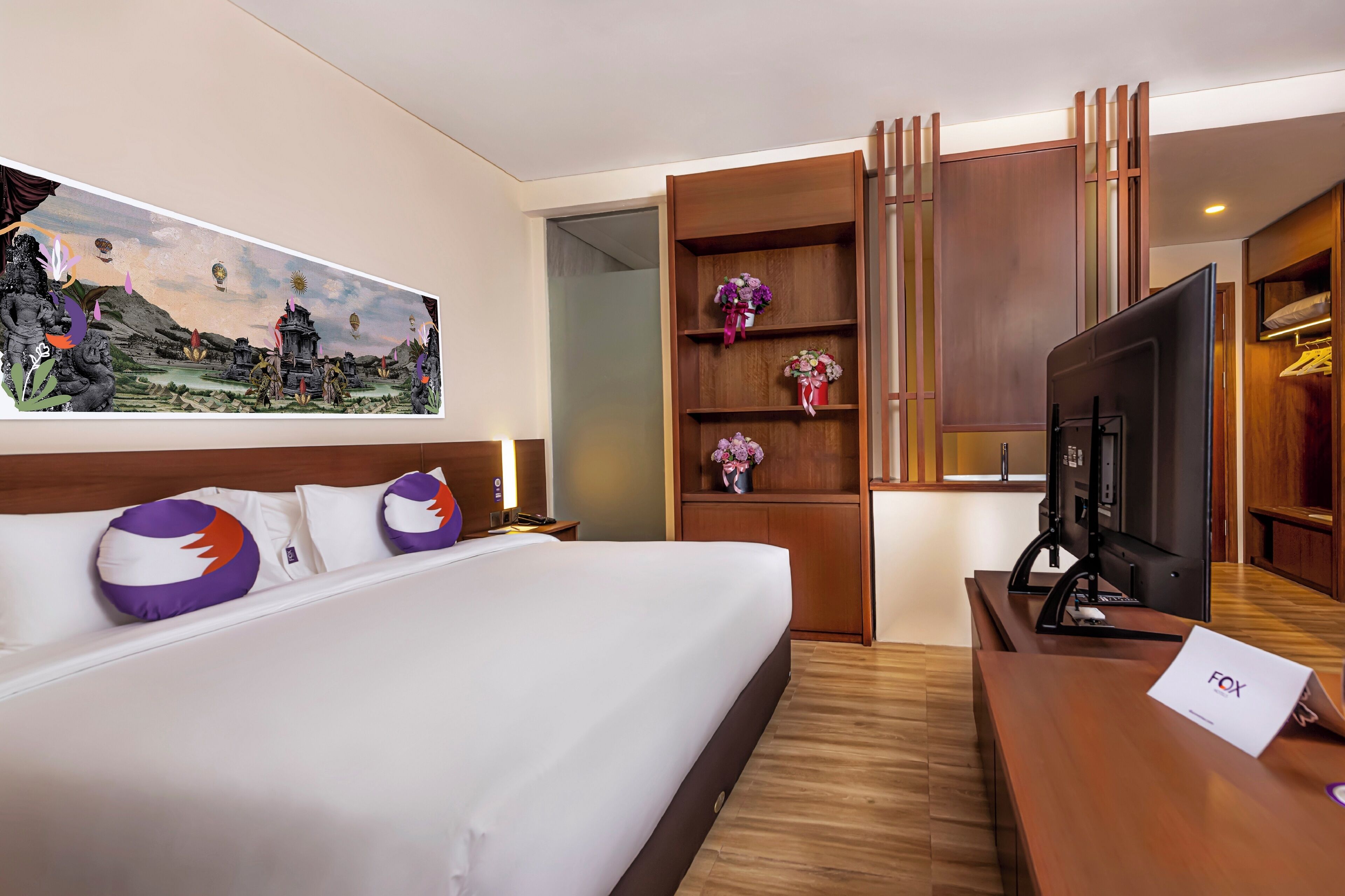 Ein Hotelzimmer mit Bett, Fernseher, Schreibtisch und einem Gemälde an der Wand.