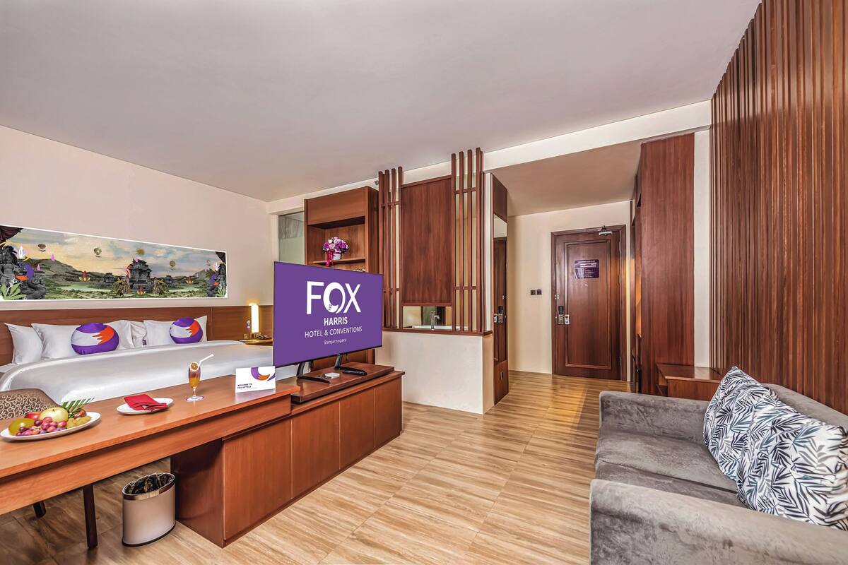 Ein Hotelzimmer mit Bett, Schreibtisch, Sofa, Fernseher und einem Bild an der Wand.