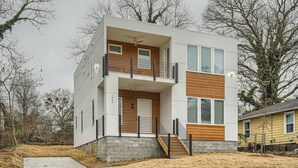 Et moderne hus i to etager med stensokkel, træterrasse og en lille forhave.