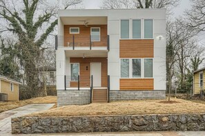 A modern two-story house with a stone foundation, wooden accents, and a balcony.