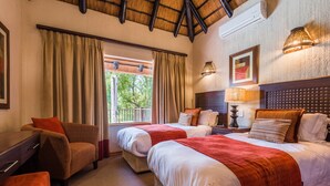Une chambre d’hôtel avec deux lits, un canapé, un bureau et une fenêtre avec des rideaux.