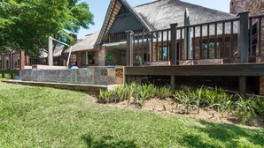 Un bâtiment doté d’un toit de chaume, d’une terrasse en bois et d’un jardin clos.