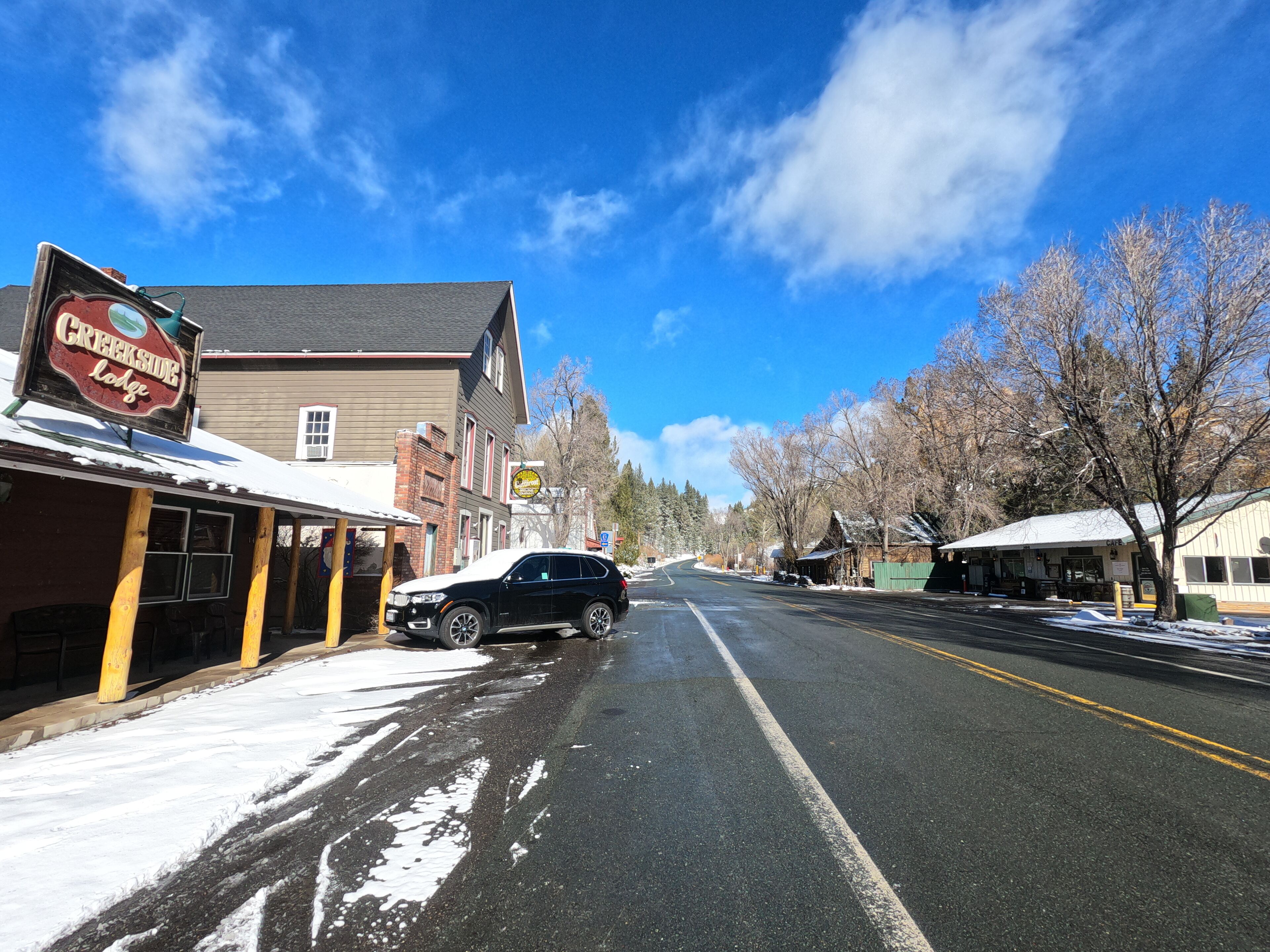 A street with a building labeled "Creekside Lodge" on the left, featuring a covered outdoor seating area.