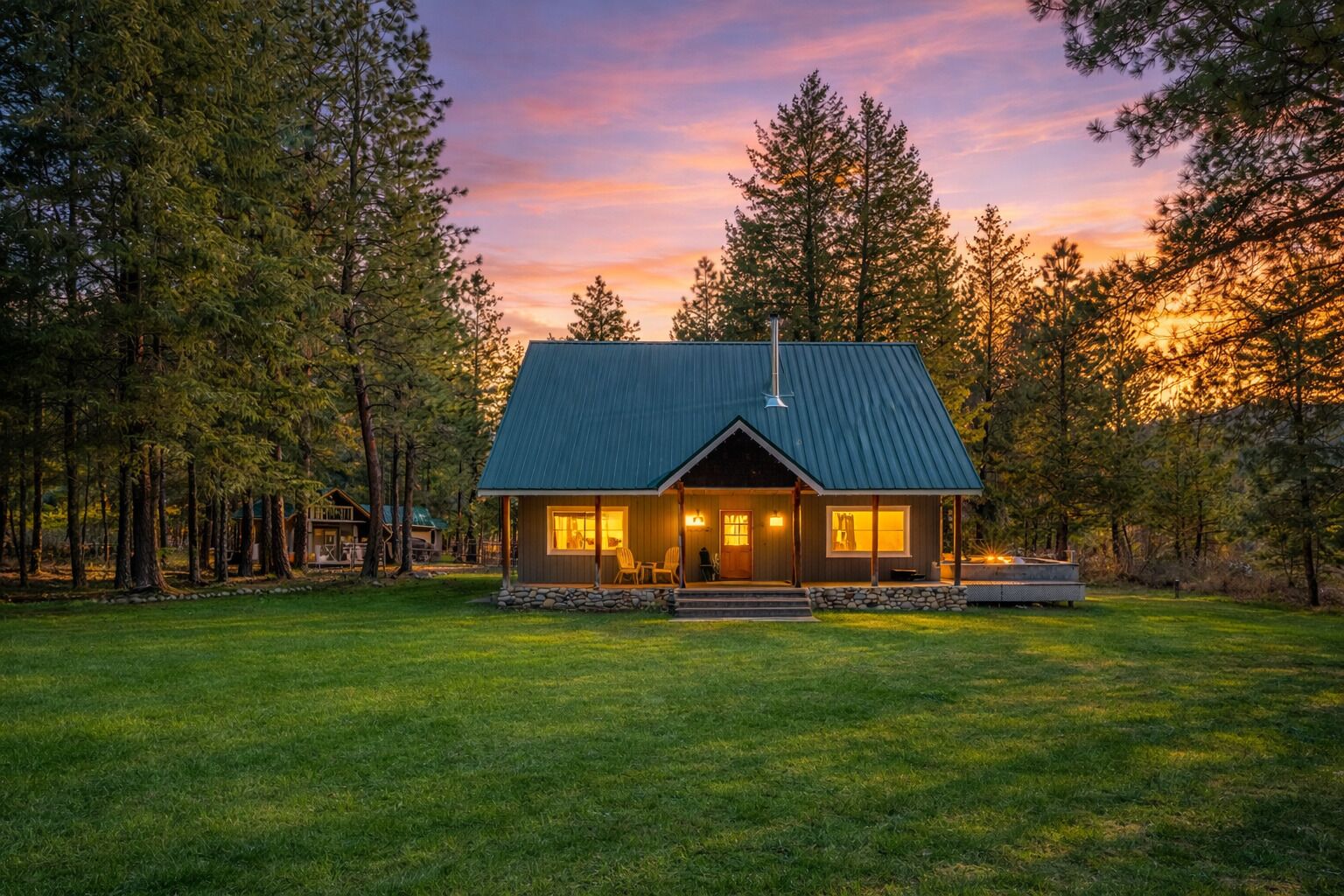 Une cabane avec un toit en métal, entourée d’arbres, et un gazon bien entretenu.