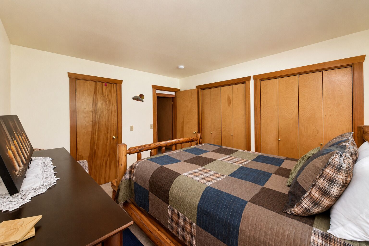 A bedroom with a bed, a desk, and a wardrobe.