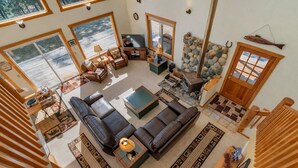 A spacious living room with a large sectional sofa, a fireplace, and a stone wall.