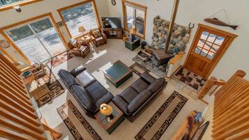 A spacious living room with a large sectional sofa, a fireplace, and a stone wall.