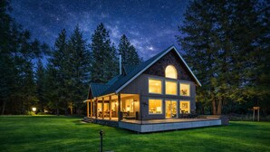 A two-story house with a large porch, surrounded by a well-maintained lawn and tall trees.