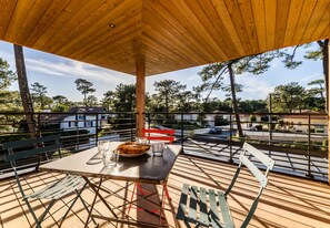 An outdoor patio with a table set for two, surrounded by metal railings and wooden deck flooring. - SPRING . KEYWEEK - Contemporary villa with pool in the hea (Anglet)