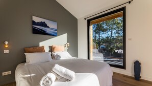 A modern bedroom with a large bed, a view of the outdoors through a sliding door, and a mountain landscape painting on the wall. - SPRING . KEYWEEK - Contemporary villa with pool in the hea (Anglet)