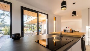 A modern kitchen with a large island, black appliances, and a view to the outside. - SPRING . KEYWEEK - Contemporary villa with pool in the hea (Anglet)