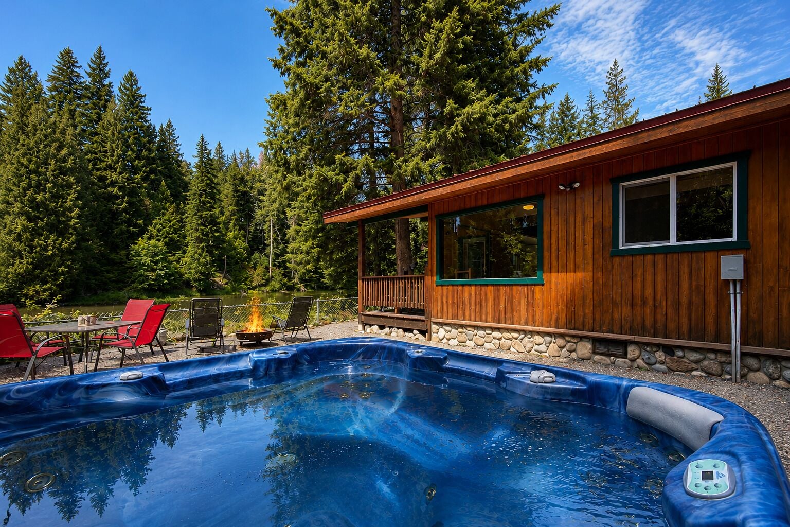 A hot tub with a wooden deck, surrounded by a forest, and a building with large windows.